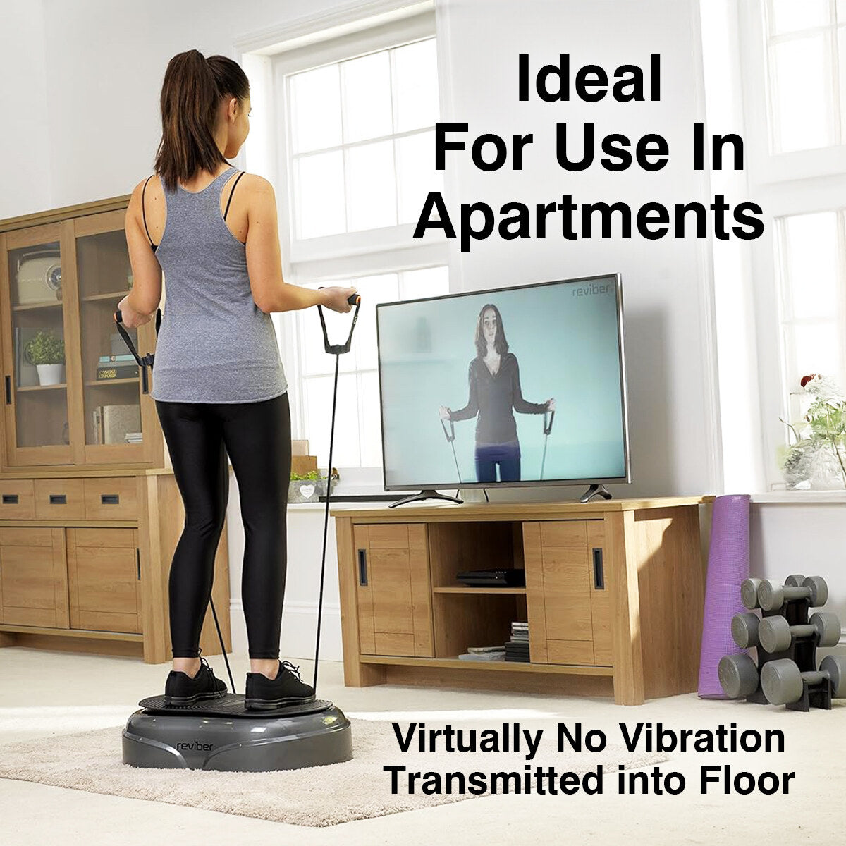A woman works out on the Reviber Fusion Oscillating Vibration Plate Exerciser by Reviber in her living room with resistance bands, following a TV instructor. Ideal for use in apartments—virtually no vibration transmitted into the floor.