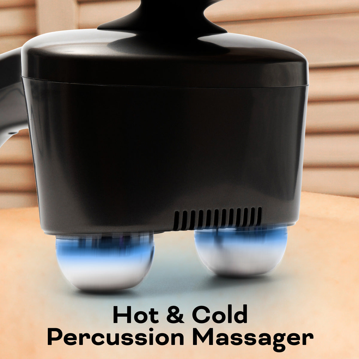 A close-up of the Reviber Hot and Cold Percussion Massager by Reviber shows its two metal heads—one glowing blue—applied to bare skin in a wooden room, offering soothing muscle relief with both hot and cold modes.